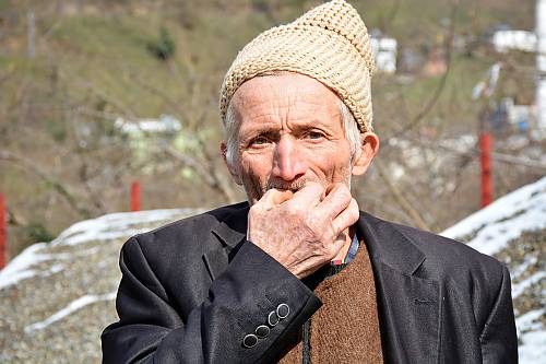 An elderly man blowing a whistle.